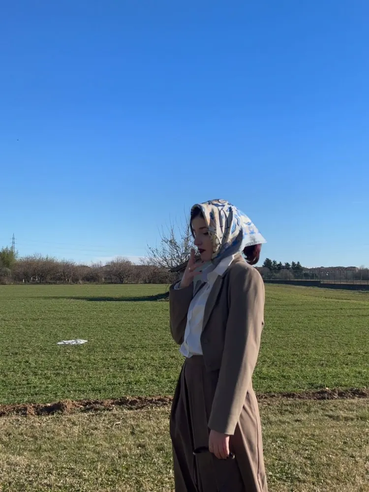 Darlie Ole con un foulard in testa in un campo aperto sotto il cielo azzurro