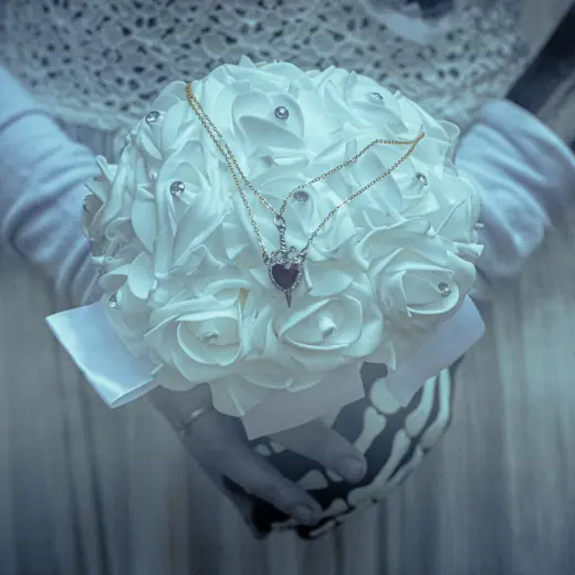 Bouquet di rose bianche stretto da guanti a scheletro