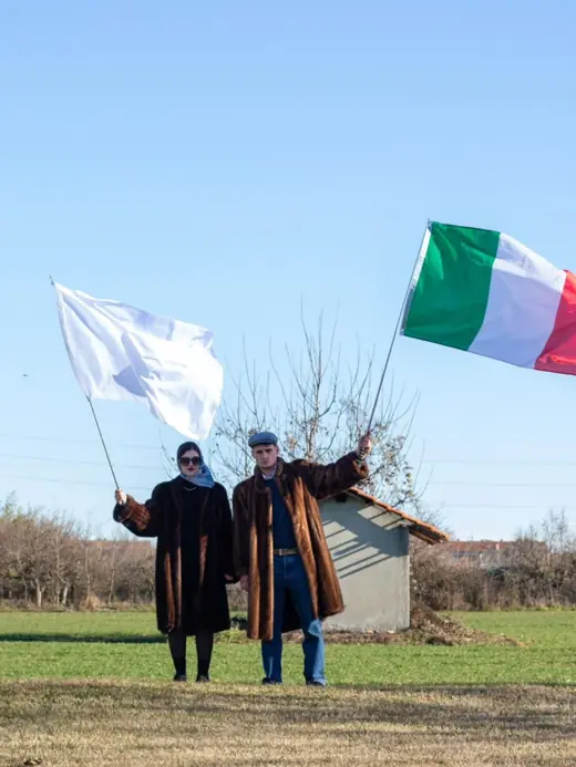 Due figure reggono la bandiera bianca e il tricolore